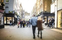 A pedestrianised high street with shoppers walking down it.