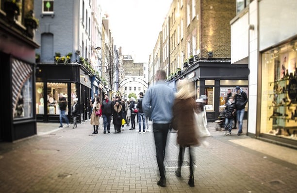 A pedestrianised high street with shoppers walking down it.