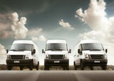 3 white delivery vans facing forward against a cloudy sky background