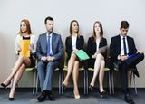 5 people sitting in a row waiting for a job interview