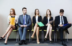 5 people sitting in a row waiting for a job interview