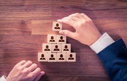 Hands arranging wooden blocks with a person icon on them