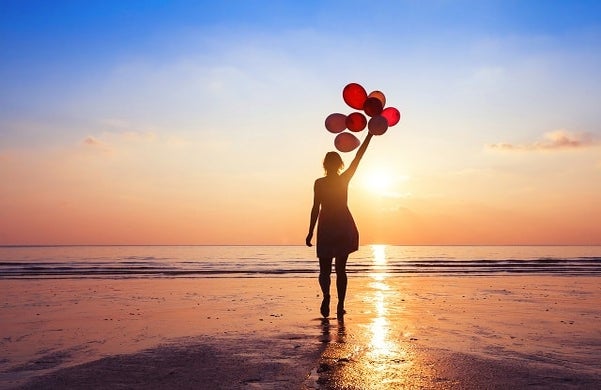 A woman on a beach holding balloons