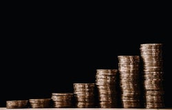 growing piles of gold coins on a table with a black background
