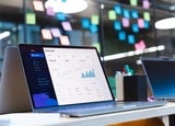 CRM software is displayed on a laptop in front of a wall of sticky notes
