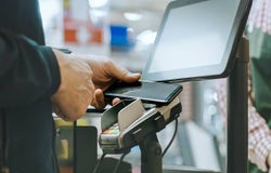 Close up of a mobile phone tapping a card reader to make payment in a shop