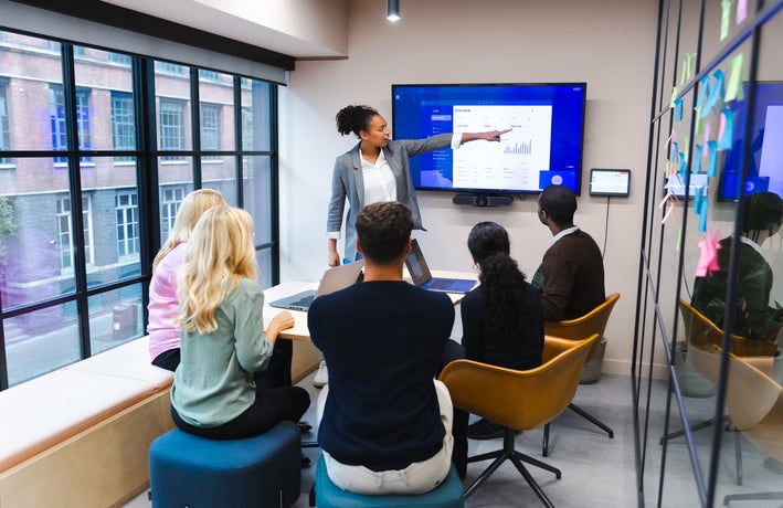 A woman points to a presentation screen in a meeting