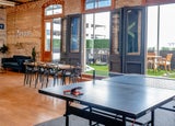 a modern workplace with a meeting table, outdoor space and ping pong table, representing company culture