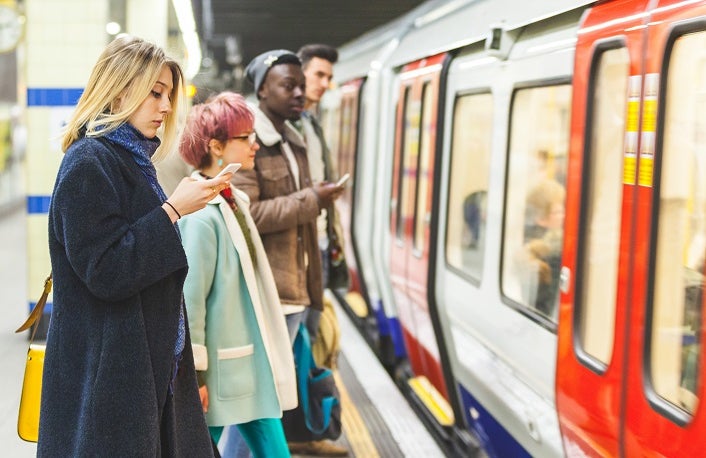 People waiting for the train at subway station. Mixed race persons, two men and two women, staying on a line and waiting to board the train. Commuting and transport