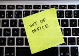Image of a post-it note stuck to an office keyboard with the words 'OUT OF OFFICE' written on it