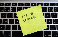 Image of a post-it note stuck to an office keyboard with the words 'OUT OF OFFICE' written on it