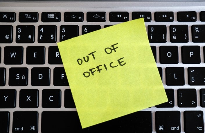 Image of a post-it note stuck to an office keyboard with the words 'OUT OF OFFICE' written on it