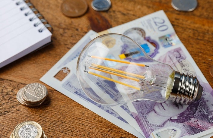 counting monthly expenses, electricity bills, money and payments, doing paperwork with energy efficient led filament Lightbulb Glowing, Devon, United Kingdom April 19 2021.