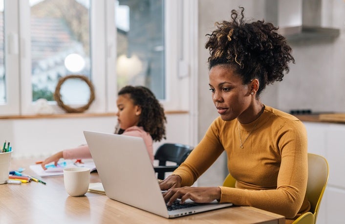 Mom is working from home with her daughter sitting next to her