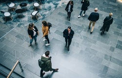 Crowd of people in modern office building hallway. Business people walking across office lobby.