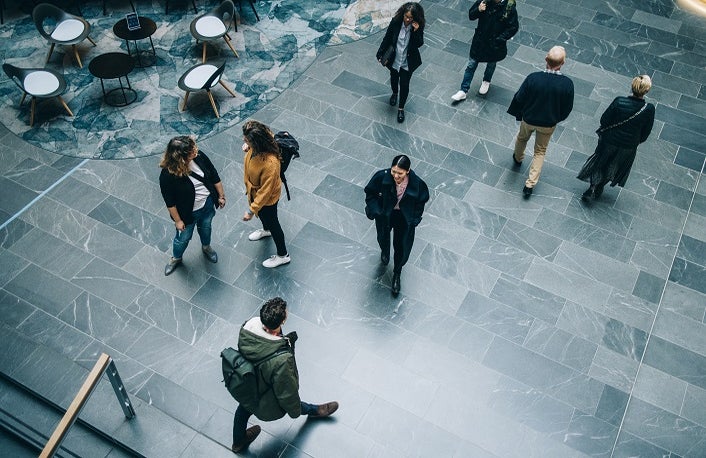 Crowd of people in modern office building hallway. Business people walking across office lobby.