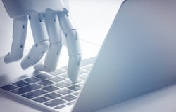 Robot hand touching a keyboard of a Mac computer about to type