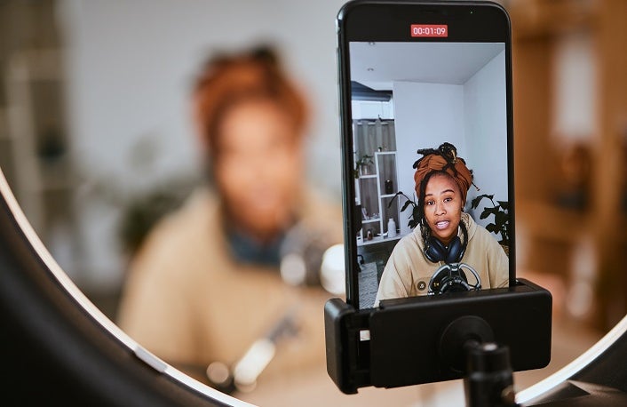 Communication, phone and black woman streaming podcast, radio talk show or speaker talking about teen culture. Online broadcast microphone, ring light or gen z influencer speaking about student news.