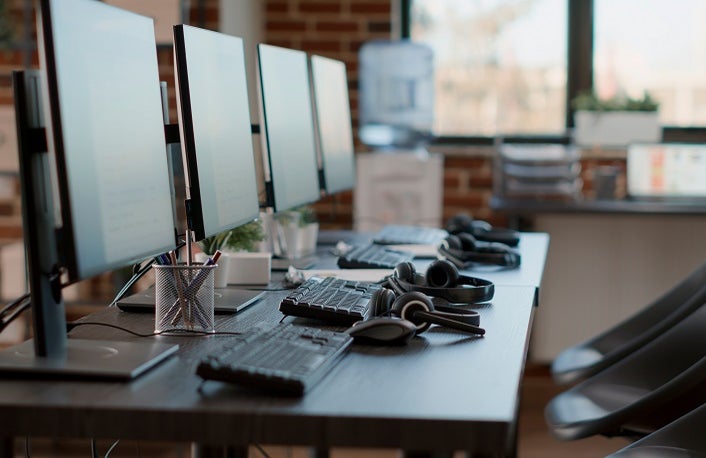 Empty customer service workstation to help telemarketing clients, modern call center technology for sales assistance and support. No people in office with monitors and headphones.