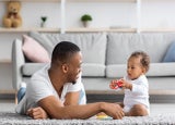 Shared Parental Leave. Young Black Father Playing With Little Baby At Home