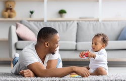 Shared Parental Leave. Young Black Father Playing With Little Baby At Home