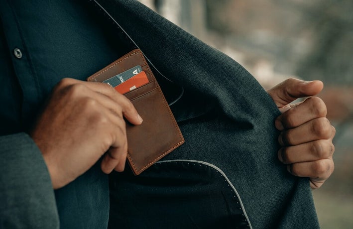 man taking wallet full of credit cards out of pocket