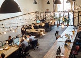 An industrial-looking co-working space filled with desks and people