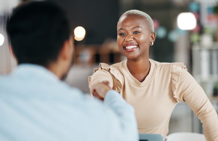 Black, female woman shaking hands with white male to seal an agreement