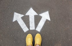 Woman standing near arrows on asphalt, top view. Choice concept
