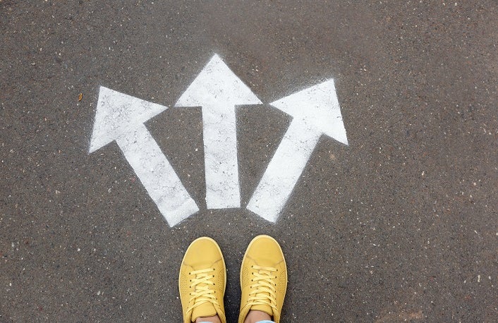 Woman standing near arrows on asphalt, top view. Choice concept