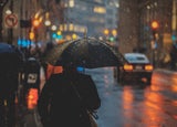 Man on a street in the rain with an umbrella