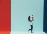 a woman holds her baby aloft against a colourful painted wall