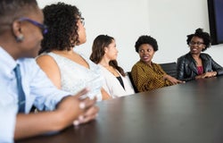 a group of businesswomen speaking at a table