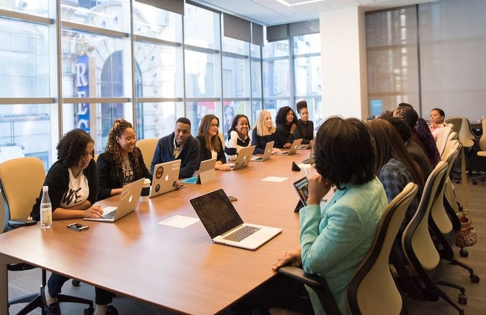 a group of people sat around a workplace meeting table in discussion