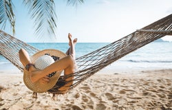 Summer travel vacation concept, Happy traveler asian woman with white bikini relax in hammock on beach in Koh mak, Thailand