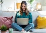 Shot of woman working with laptop while sitting on couch in living room at home