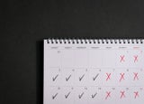 Calendar with ticks and crosses, depicting four day work week concept. Copy space.
