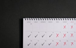 Calendar with ticks and crosses, depicting four day work week concept. Copy space.