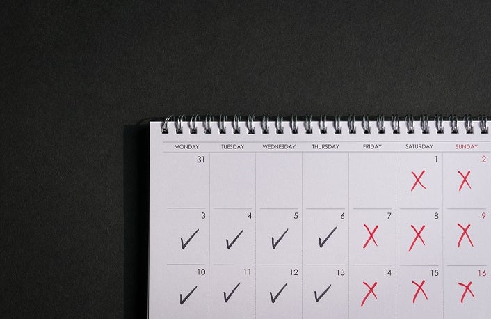 Calendar with ticks and crosses, depicting four day work week concept. Copy space.