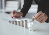 Person with pile of coins and piggy bank, money saving concept for future use and financial stability, salary management, personal finance, investment savings.