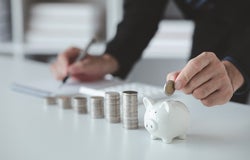 Person with pile of coins and piggy bank, money saving concept for future use and financial stability, salary management, personal finance, investment savings.