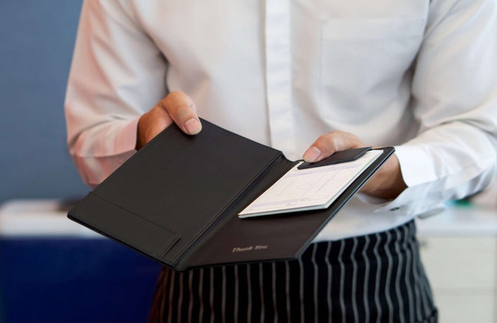 Waitress holding out a bill to a customer to add a service charge