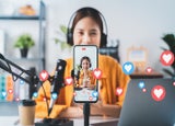 Vlogger live streaming podcast review on social media, Young Asian woman use microphones wear headphones with laptop record video. Content creator concept.