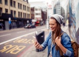 Young Caucasian woman using a smartphone while commuting on the streets of London UK