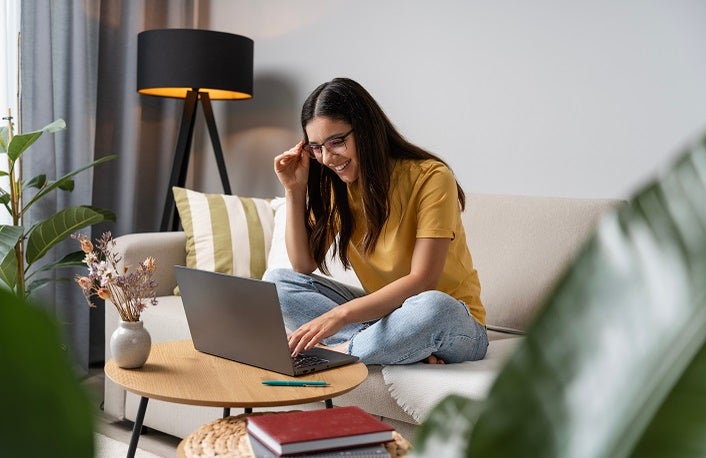 Back to study. Happy student doing her work at home on laptop in a cosy room.