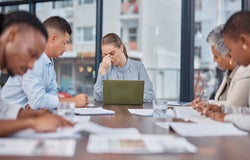 Business people, team and woman with headache in meeting at office, mistake and fail. Stress, group and person frustrated in problem, financial crisis or fear for challenge of tax debt in bankruptcy.