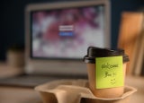 Back to Work Concept. Closeup of Welcome Note on Takeaway Coffee Cup in Office Desk. Message from a Colleague or Boss