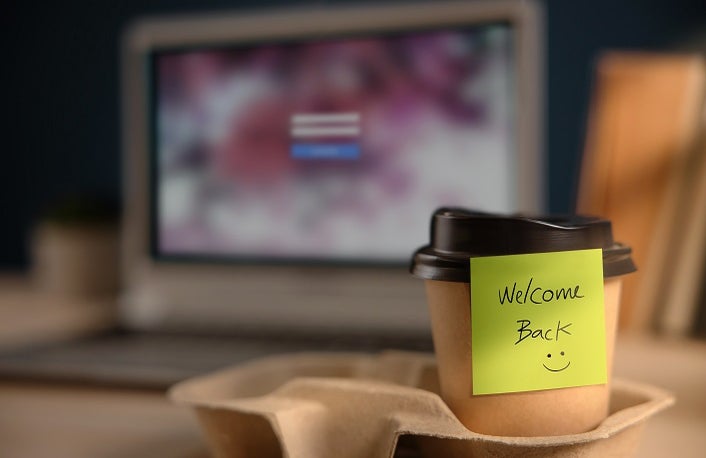 Back to Work Concept. Closeup of Welcome Note on Takeaway Coffee Cup in Office Desk. Message from a Colleague or Boss
