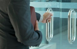 Businessman entering an office by opening out a glass door