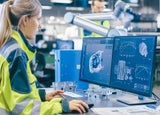 a woman sits at her desk in a manufacturing industry setting